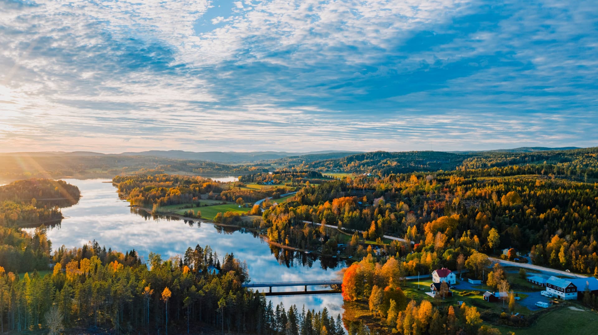 Svenskt landskap med sjö och höstskog i soluppgång